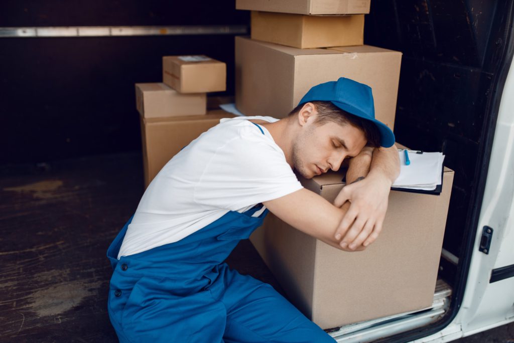 Tired loader sleeping on stack of parcels
